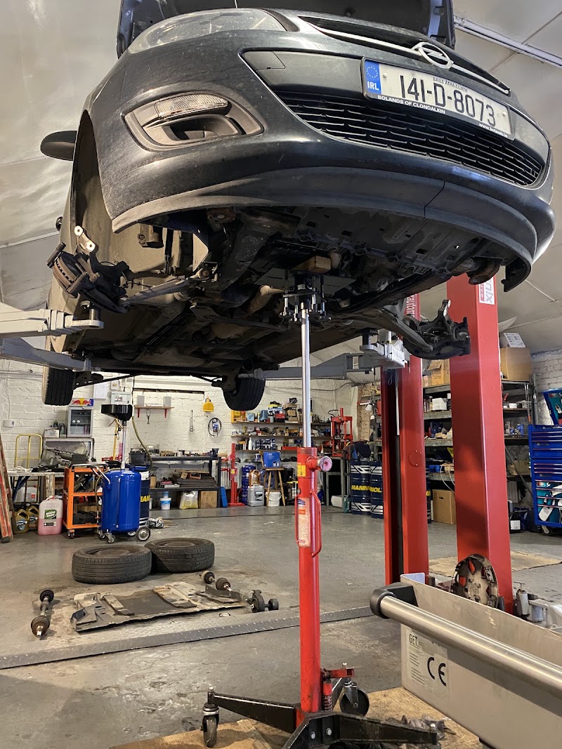 A car up on a red two-post lift in the workshop, wheel off for brake work